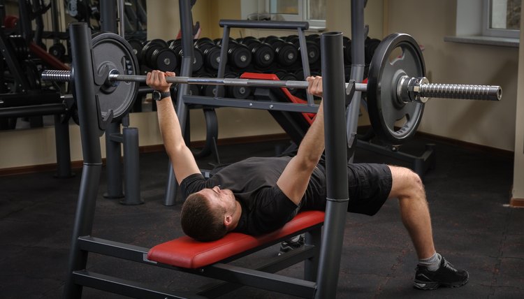 handsome young man doing bench press workout in gym