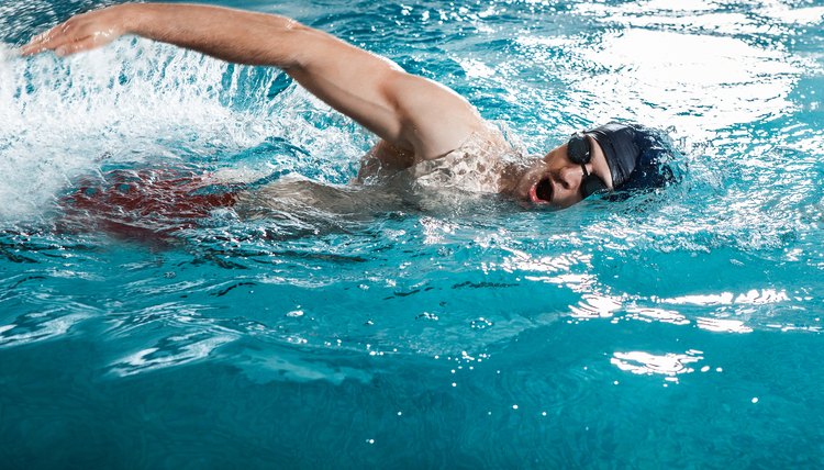 Young man swimming the front crawl in a pool