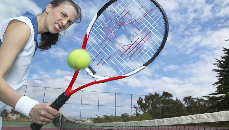 Woman holding tennis racket with hole in it and tennis ball in air