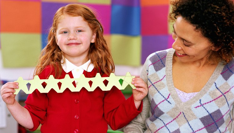 Child holding up paper chain in classroom.