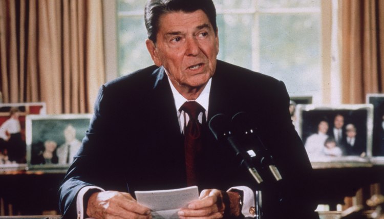 President Ronald Reagan sitting at his desk in the Oval Office, circa 1985