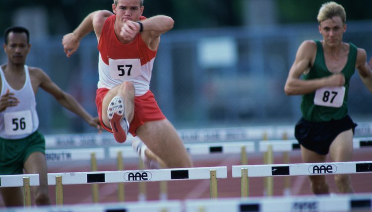 Male runners jumping hurdles in a race