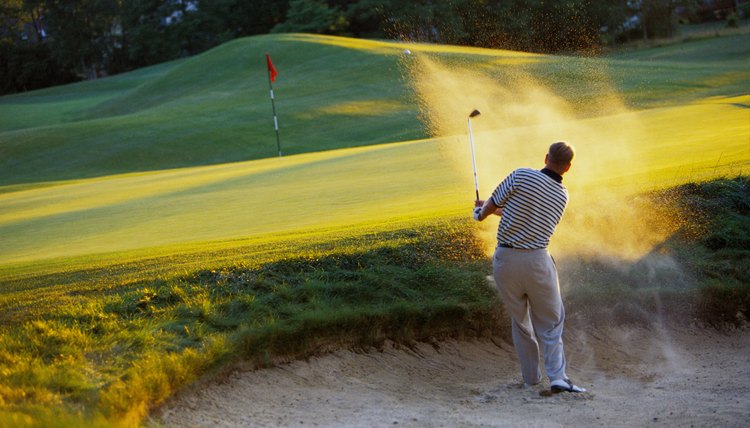 Man hitting golf ball out of sand trap