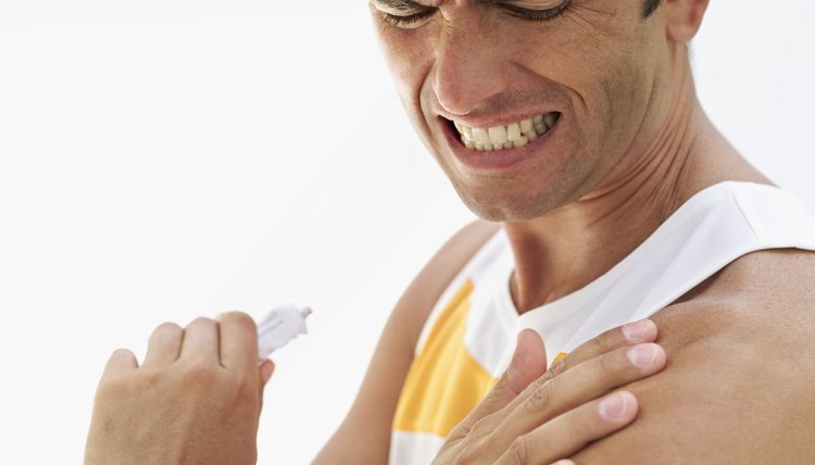 side profile of a mid adult man applying ointment on his shoulder