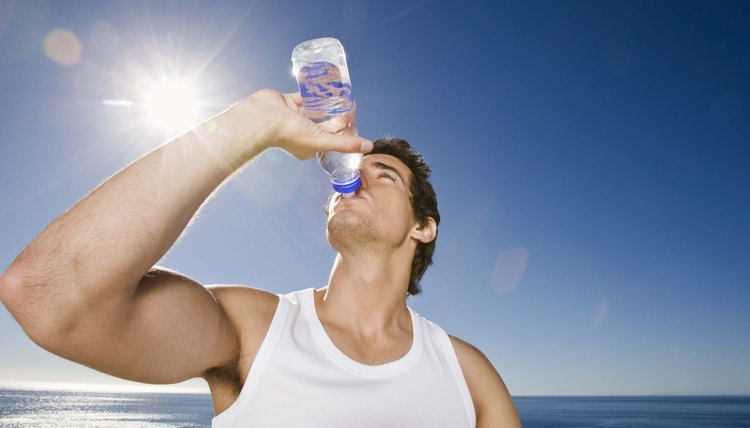 Man drinking bottle of water outdoors after workout