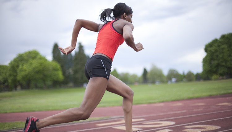 Young female sprinter accelerating, running, side view