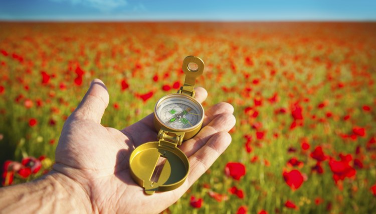 Man's hand holding a modern compass.