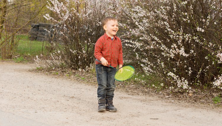 Laughing little boy playing in the a badminton