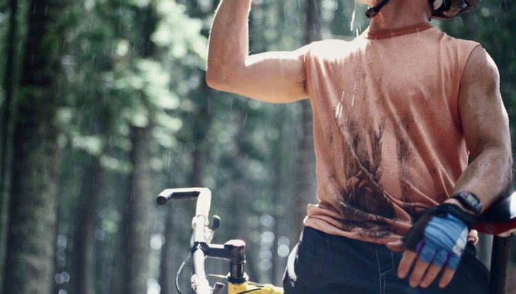 Man resting from mountain biking, drinking from water bottle