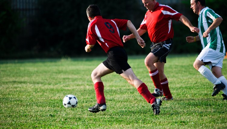 Soccer players chasing ball in game