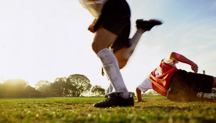 Soccer players running on pitch, low section (blurred motion)