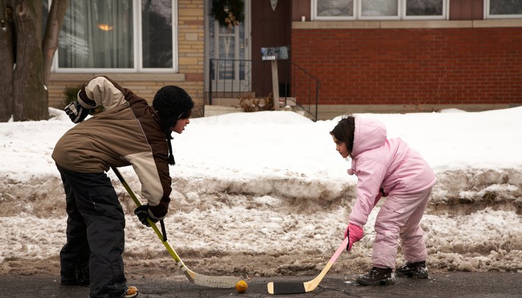 Siblings playing hockey on street