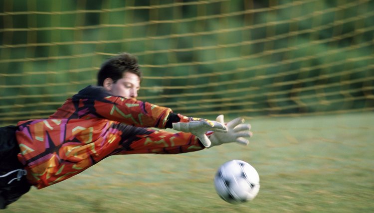 Goalie diving on a field to save the ball