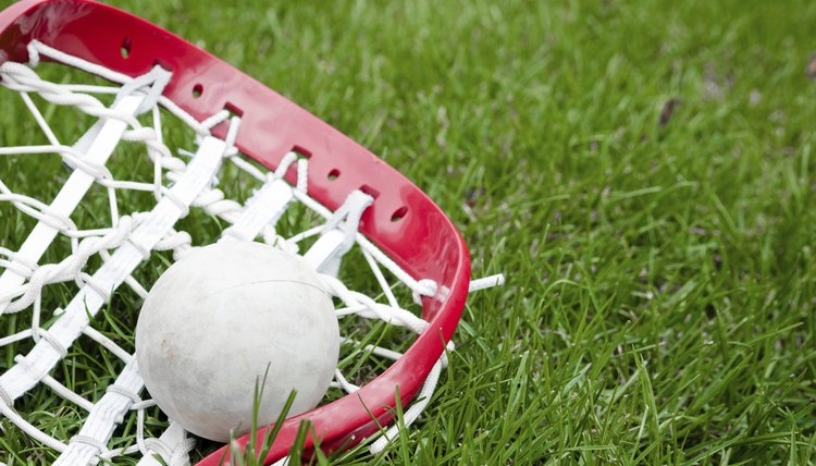 Girls lacrosse head and grey ball on grass