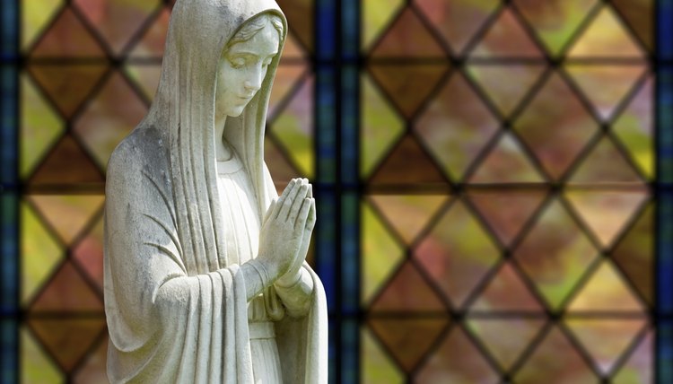 A statue of mother mother in front of a stained glass window.