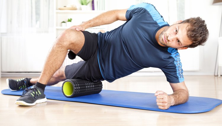 Athletic Man in Side Planking Using Foam Roller