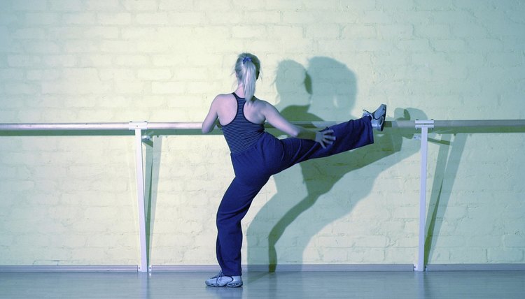 Back of woman doing leg raises at bar in gym