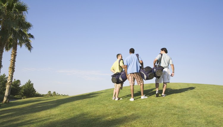 Rear view of three men walking on golf course
