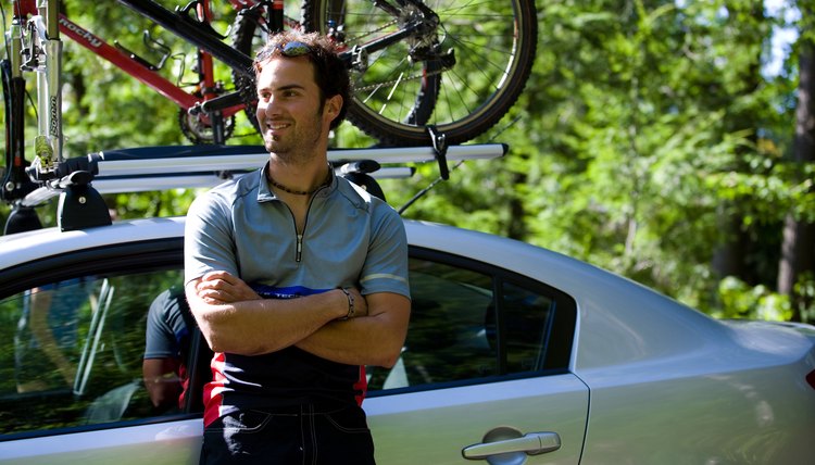 Smiling man posing by car with bike rack