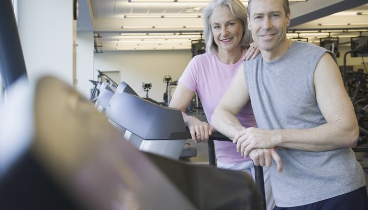 Couple standing on treadmill at gym
