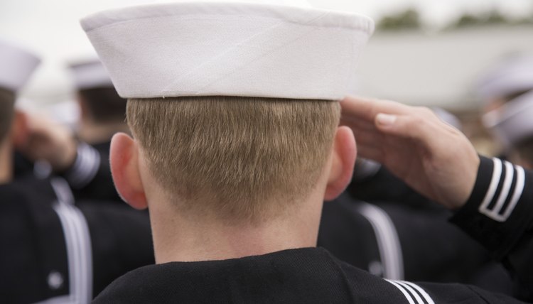 A Navy sailor carries an umbrella in his left hand so his right hand is free to salute.