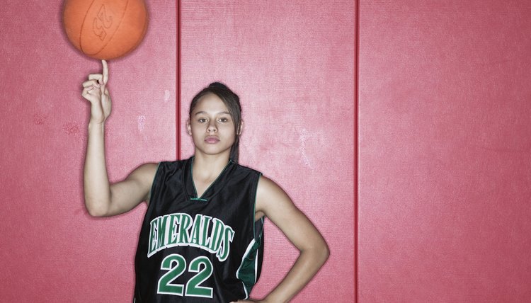 Teenage girl spinning a basketball on her finger on a basketball court