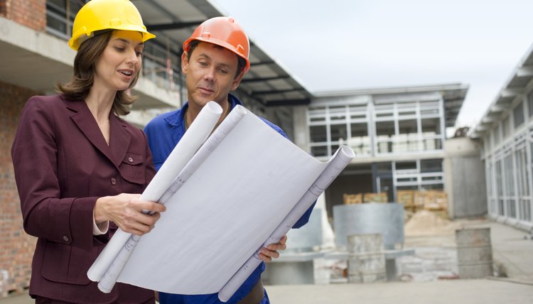 Businesswoman reading blueprints with foreman