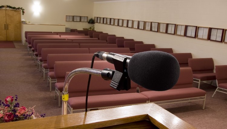 A close-up of a microphone on the podium in front of church pews.