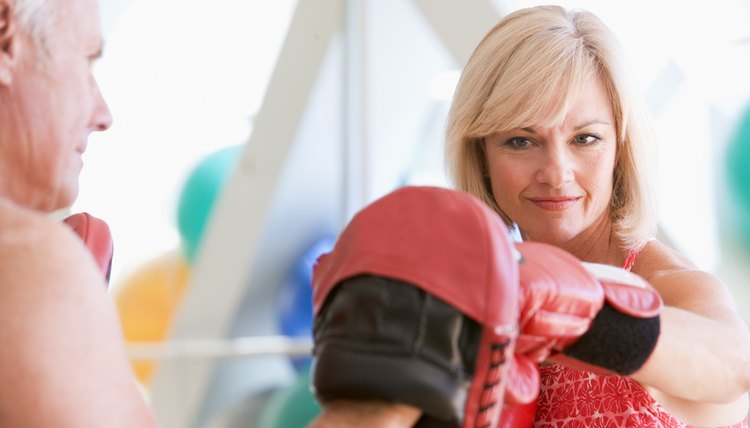 Woman Boxing With Personal Trainer At Gym