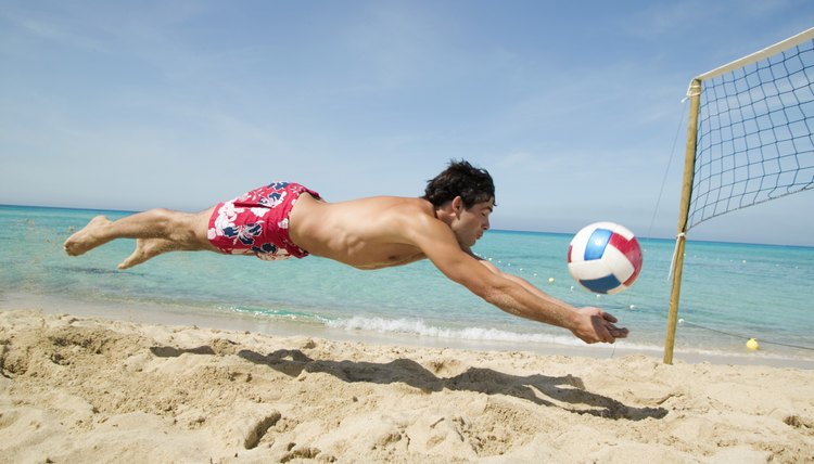 Man diving for volleyball at beach