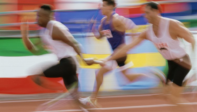 Side profile of runners exchanging baton at a relay race