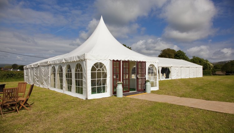 Bright white wedding tent set up on green field.