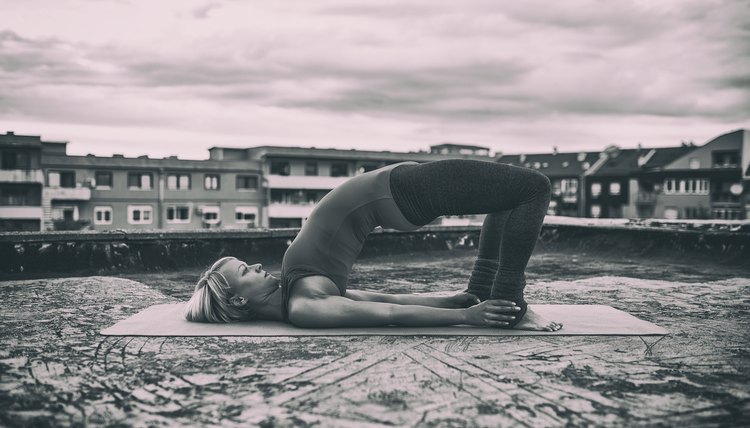 Beautiful woman practicing yoga on the roof.Image is intentionally toned.
