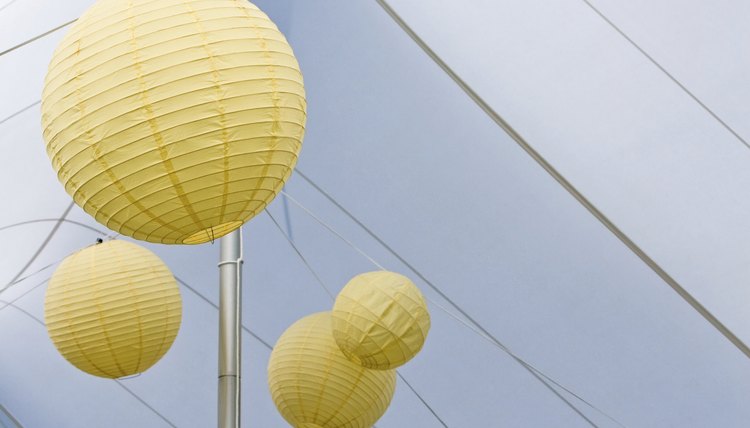 Paper lanterns hang from the apex of an outdoor tent.