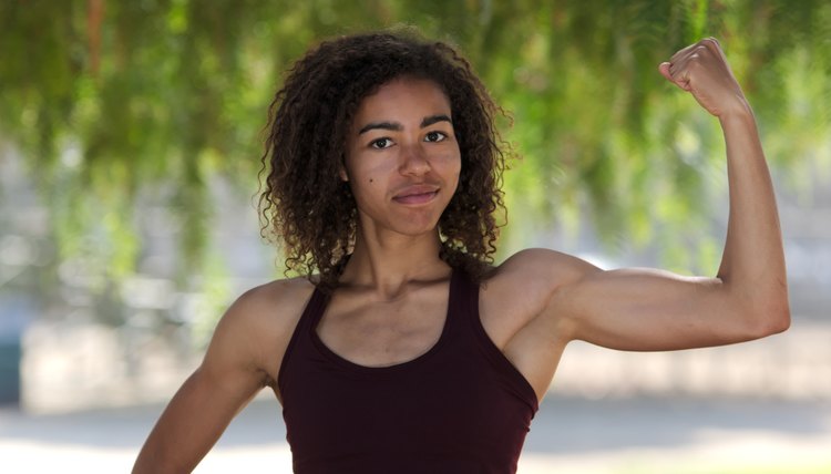 Young strong woman curling bicep with fist in air