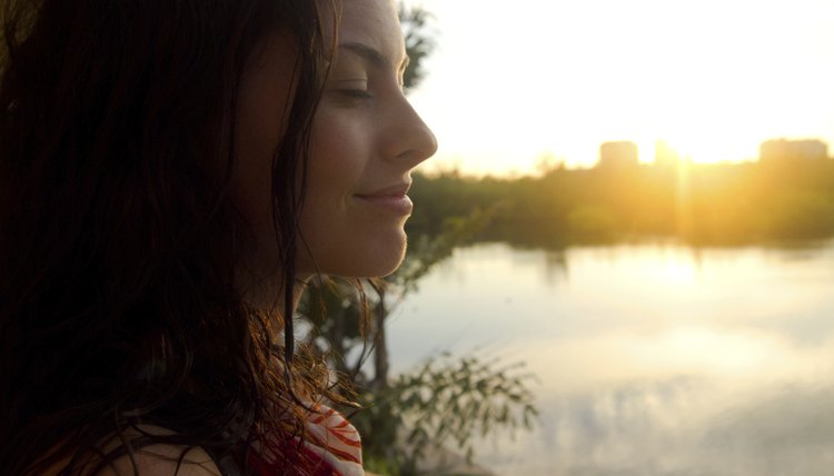 A woman meditating by a city lake in the morning.