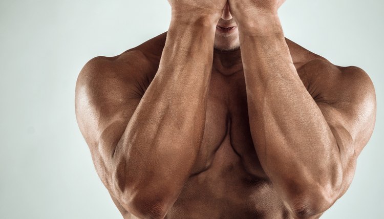 Two Power Mans Hands in Front of Face. Close-up of a man's fists and abs. Strong man's arm with muscles and veins.