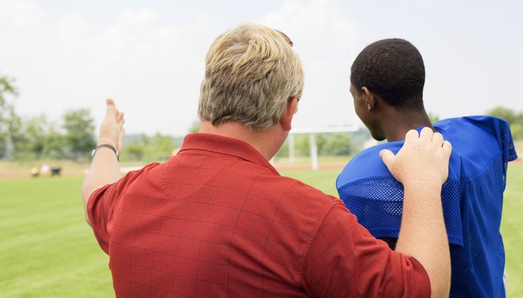 Coach talking to boy in football gear