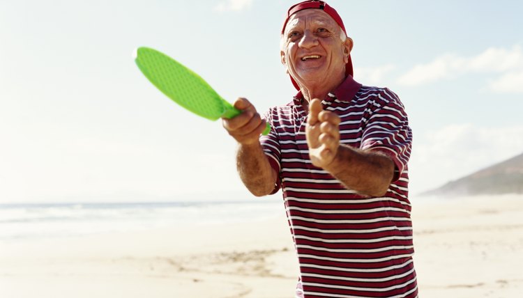 Senior man playing beach tennis, smiling