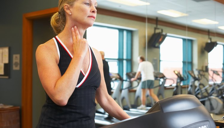 Woman checking her pulse on treadmill at gym