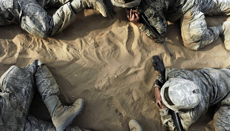 Soldiers in basic training crawl through an obstacle course.