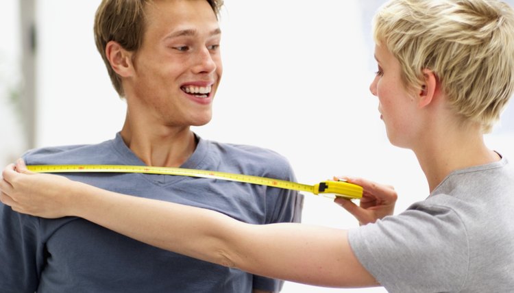 young woman measuring young man's chest with a measuring tape