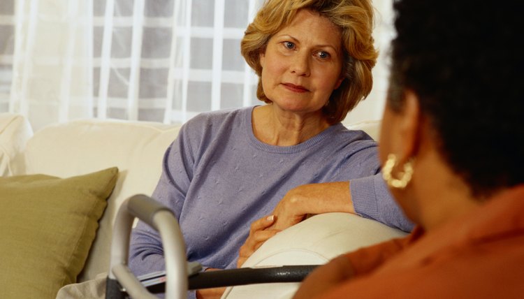 Two women talk on a couch.