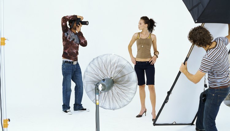 Photographer taking a photograph of a young woman in a studio