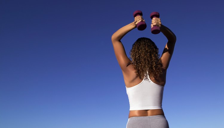 Rear view of a woman using hand weights exercising her shoulders and triceps.