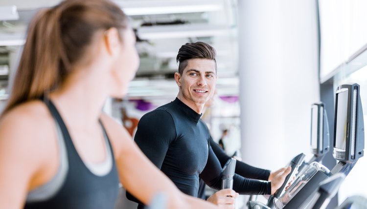 Handsome man and woman using a stepper in a gym