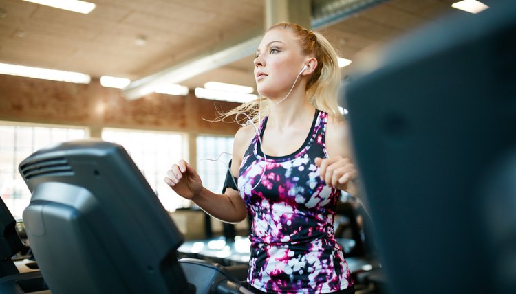 Young female running on treadmill in health club