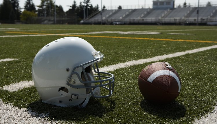 Football and football helmet on football field