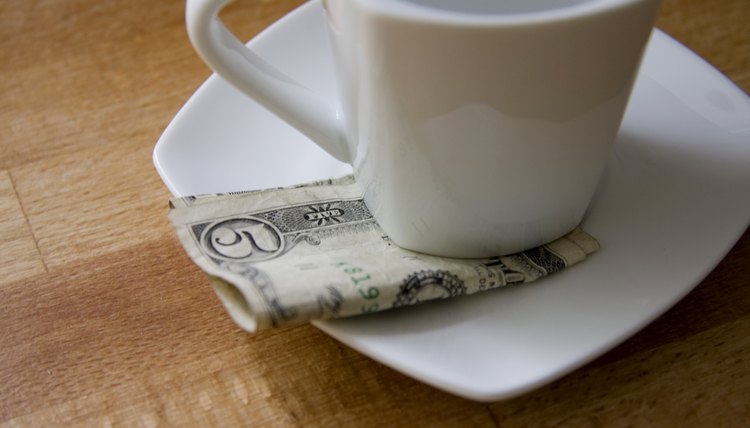 A five dollar bill tucked beneath a coffee cup in a cafe.