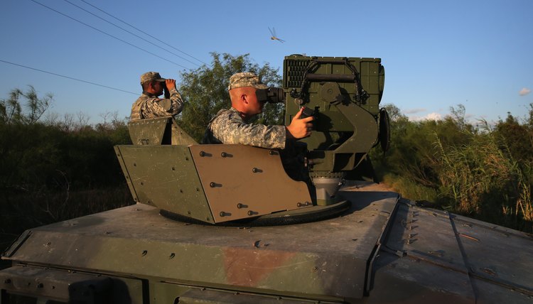 Two army soldiers looking out from top of tank